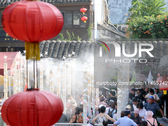 Tourists are waiting to board a boat at a cruise terminal installed with spray cooling devices in Suzhou, China, on August 8, 2024. (