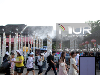 Tourists are waiting to board a boat at a cruise terminal installed with spray cooling devices in Suzhou, China, on August 8, 2024. (