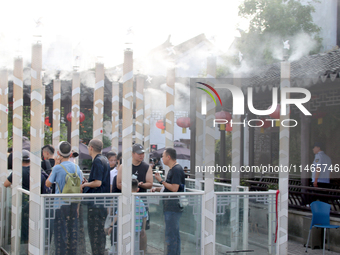 Tourists are waiting to board a boat at a cruise terminal installed with spray cooling devices in Suzhou, China, on August 8, 2024. (