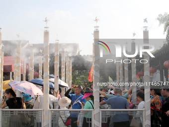 Tourists are waiting to board a boat at a cruise terminal installed with spray cooling devices in Suzhou, China, on August 8, 2024. (