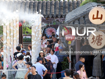 Tourists are waiting to board a boat at a cruise terminal installed with spray cooling devices in Suzhou, China, on August 8, 2024. (