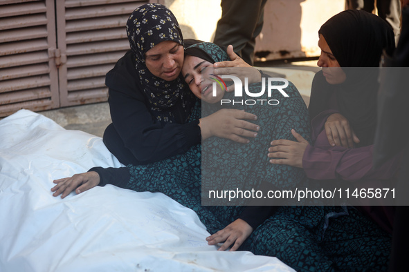 Palestinians are mourning by the bodies of relatives killed in Israeli bombardment on Nuseirat in the central Gaza Strip at Al-Aqsa Martyrs...