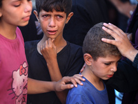 Palestinians are mourning by the bodies of relatives killed in Israeli bombardment on Nuseirat in the central Gaza Strip at Al-Aqsa Martyrs...