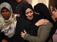 Palestinians are mourning by the bodies of relatives killed in Israeli bombardment on Nuseirat in the central Gaza Strip at Al-Aqsa Martyrs...