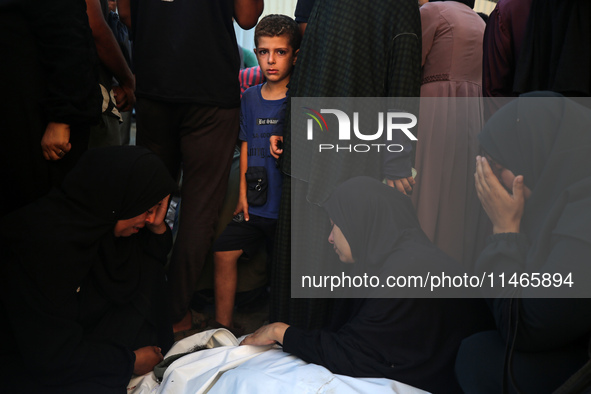 Palestinians are mourning by the bodies of relatives killed in Israeli bombardment on Nuseirat in the central Gaza Strip at Al-Aqsa Martyrs...