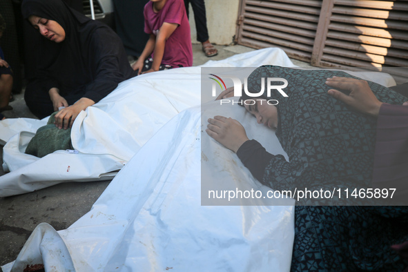 Palestinians are mourning by the bodies of relatives killed in Israeli bombardment on Nuseirat in the central Gaza Strip at Al-Aqsa Martyrs...