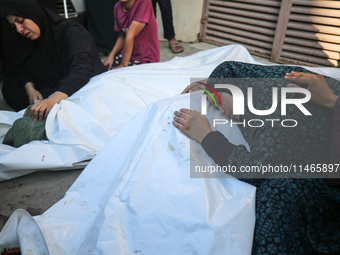 Palestinians are mourning by the bodies of relatives killed in Israeli bombardment on Nuseirat in the central Gaza Strip at Al-Aqsa Martyrs...