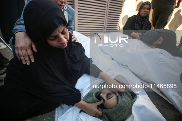 Palestinians are mourning by the bodies of relatives killed in Israeli bombardment on Nuseirat in the central Gaza Strip at Al-Aqsa Martyrs...