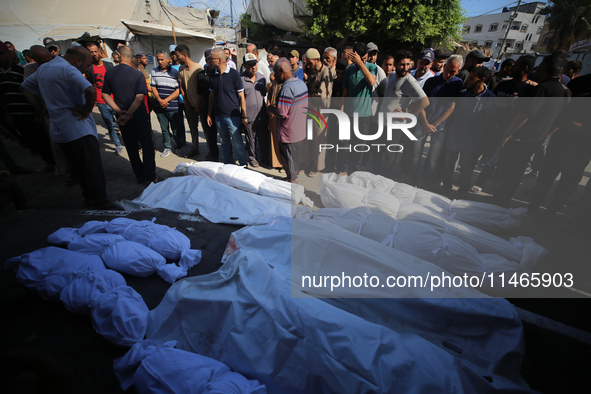 People are praying near the bodies of Palestinians killed in Israeli strikes, amid the Israel-Hamas conflict, at Al-Aqsa Martyrs Hospital in...