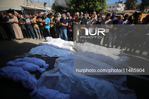 People are praying near the bodies of Palestinians killed in Israeli strikes, amid the Israel-Hamas conflict, at Al-Aqsa Martyrs Hospital in...