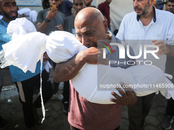 Palestinians are mourning by the bodies of relatives killed in Israeli bombardment on Nuseirat in the central Gaza Strip at Al-Aqsa Martyrs...