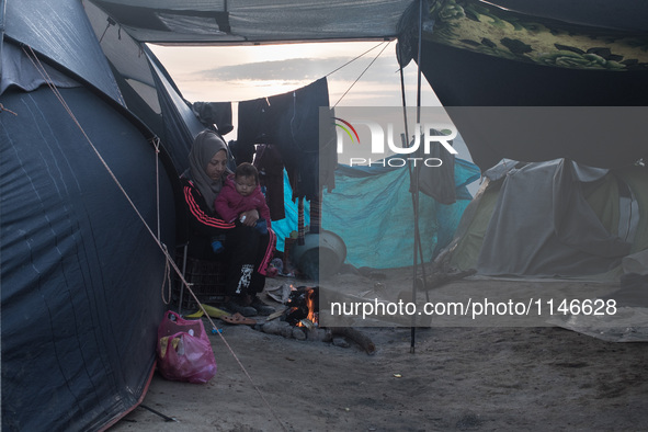 Mum and son warming up early in the morning in Idomeni camp. April 6, 2016.. A plan to send back migrants from Greece to Turkey sparked demo...