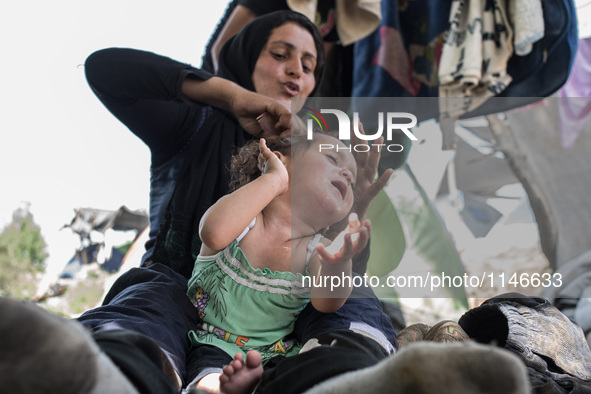 Mum brushing the hair of her daugther in Idomeni on April 6, 2016.. A plan to send back migrants from Greece to Turkey sparked demonstration...