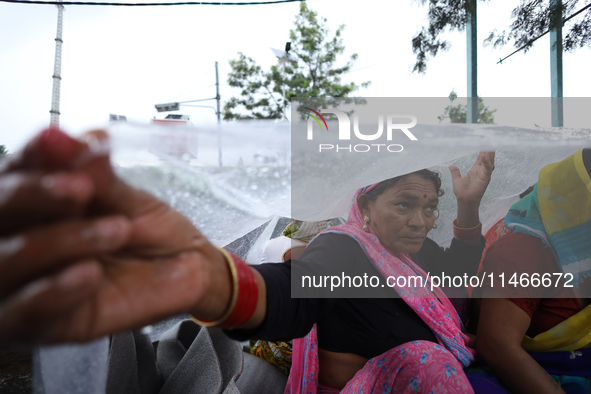 A group of human rights activists are taking shelter under plastic sheets as it is raining heavily during a sit-in protest in Kathmandu, Nep...