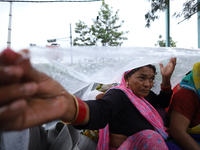 A group of human rights activists are taking shelter under plastic sheets as it is raining heavily during a sit-in protest in Kathmandu, Nep...