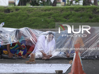 A group of human rights activists are taking shelter under plastic sheets as it is raining heavily during a sit-in protest in Kathmandu, Nep...