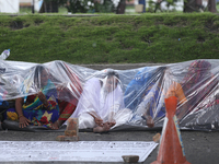 A group of human rights activists are taking shelter under plastic sheets as it is raining heavily during a sit-in protest in Kathmandu, Nep...