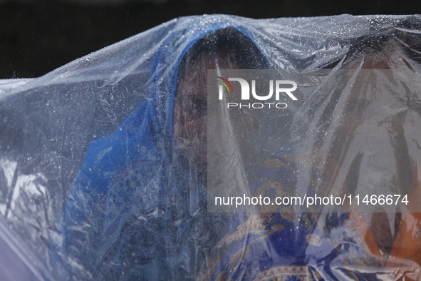 A group of human rights activists are taking shelter under plastic sheets as it is raining heavily during a sit-in protest in Kathmandu, Nep...