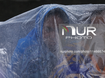 A group of human rights activists are taking shelter under plastic sheets as it is raining heavily during a sit-in protest in Kathmandu, Nep...