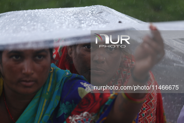 A group of human rights activists are taking shelter under plastic sheets as it is raining heavily during a sit-in protest in Kathmandu, Nep...