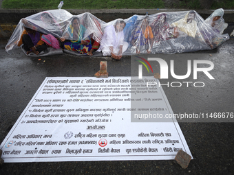 A group of human rights activists are taking shelter under plastic sheets as it is raining heavily during a sit-in protest in Kathmandu, Nep...