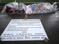 A group of human rights activists are taking shelter under plastic sheets as it is raining heavily during a sit-in protest in Kathmandu, Nep...