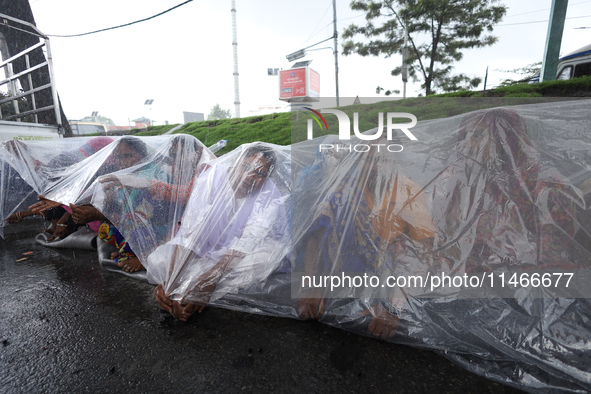 A group of human rights activists are taking shelter under plastic sheets as it is raining heavily during a sit-in protest in Kathmandu, Nep...