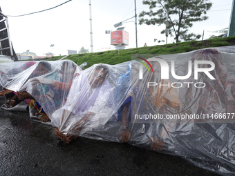 A group of human rights activists are taking shelter under plastic sheets as it is raining heavily during a sit-in protest in Kathmandu, Nep...