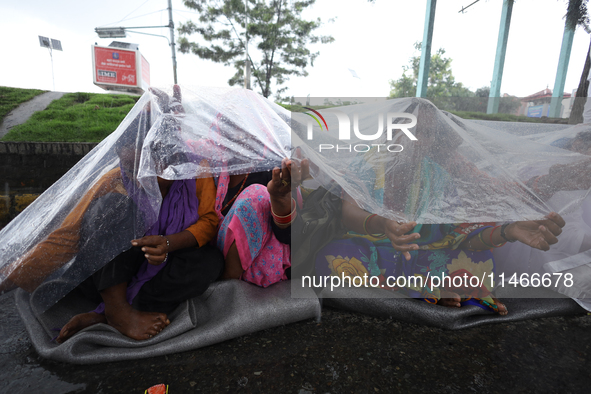 A group of human rights activists are taking shelter under plastic sheets as it is raining heavily during a sit-in protest in Kathmandu, Nep...