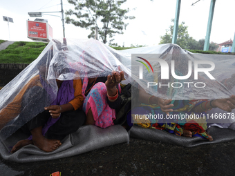 A group of human rights activists are taking shelter under plastic sheets as it is raining heavily during a sit-in protest in Kathmandu, Nep...