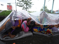 A group of human rights activists are taking shelter under plastic sheets as it is raining heavily during a sit-in protest in Kathmandu, Nep...