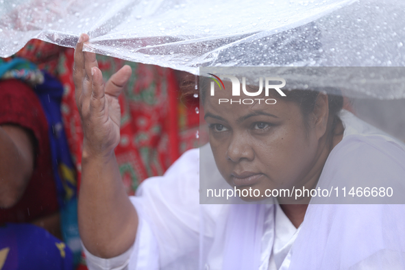 A group of human rights activists are taking shelter under plastic sheets as it is raining heavily during a sit-in protest in Kathmandu, Nep...