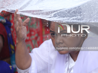 A group of human rights activists are taking shelter under plastic sheets as it is raining heavily during a sit-in protest in Kathmandu, Nep...