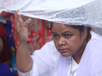 A group of human rights activists are taking shelter under plastic sheets as it is raining heavily during a sit-in protest in Kathmandu, Nep...