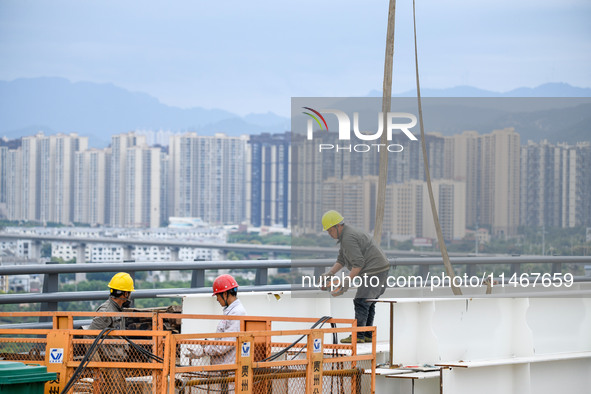 Workers are working at the construction site of Jinzhou Bridge in Xingyi, China, on August 11, 2024. 