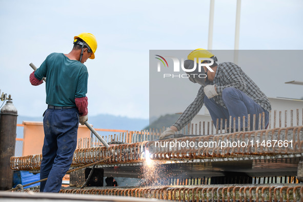 Workers are working at the construction site of Jinzhou Bridge in Xingyi, China, on August 11, 2024. 