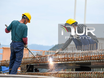 Workers are working at the construction site of Jinzhou Bridge in Xingyi, China, on August 11, 2024. (