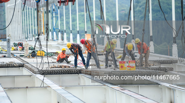 Workers are working at the construction site of Jinzhou Bridge in Xingyi, China, on August 11, 2024. 