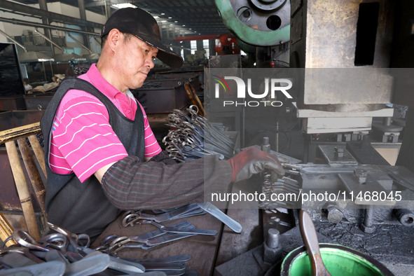 A worker of an enterprise is producing scissors on the production line at Yanshan Ocean Knife and Scissors Industrial Park in Zherong County...