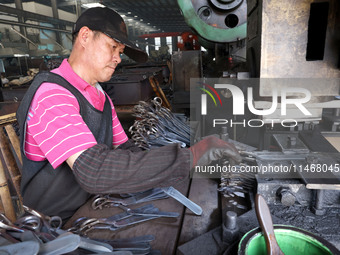 A worker of an enterprise is producing scissors on the production line at Yanshan Ocean Knife and Scissors Industrial Park in Zherong County...