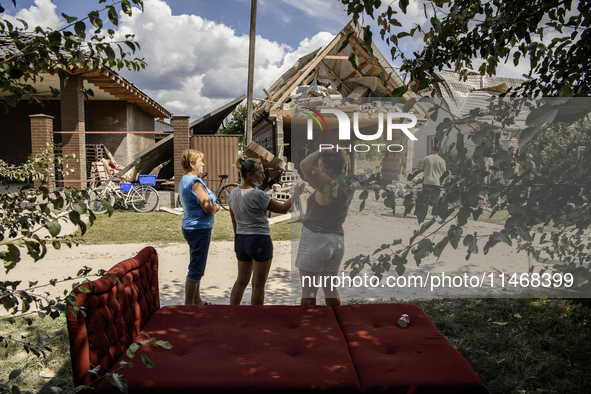 Local women are standing next to a residential building in a village in the Kyiv region, heavily damaged during a massive Russian missile an...