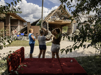 Local women are standing next to a residential building in a village in the Kyiv region, heavily damaged during a massive Russian missile an...