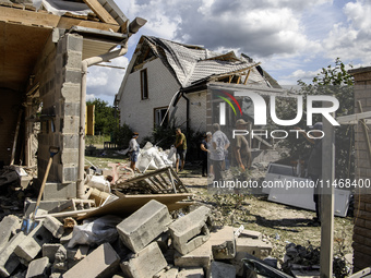 Local residents are cleaning up the residential building in a village in the Kyiv region, heavily damaged during a massive Russian missile a...