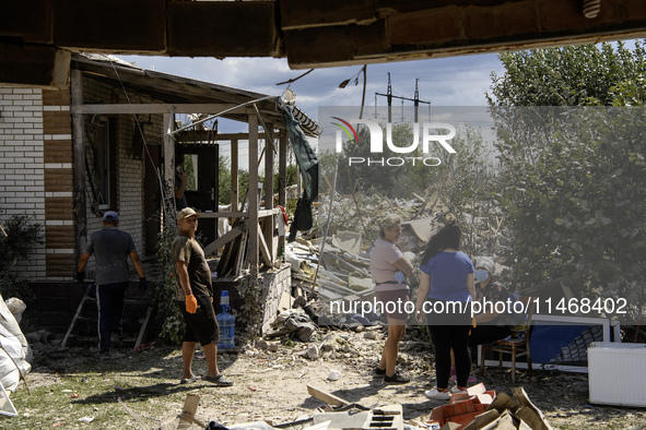 Local residents are cleaning up the residential building in a village in the Kyiv region, heavily damaged during a massive Russian missile a...