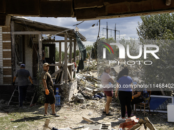 Local residents are cleaning up the residential building in a village in the Kyiv region, heavily damaged during a massive Russian missile a...