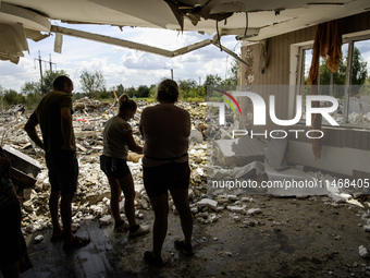 Local residents are cleaning up the residential building in a village in the Kyiv region, heavily damaged during a massive Russian missile a...