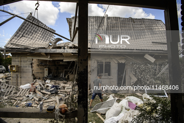 Local residents are cleaning up the residential building in a village in the Kyiv region, heavily damaged during a massive Russian missile a...