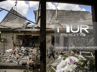 Local residents are cleaning up the residential building in a village in the Kyiv region, heavily damaged during a massive Russian missile a...