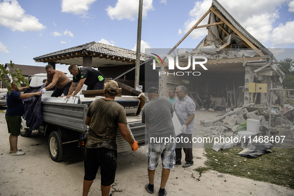 Local residents are cleaning up the residential building in a village in the Kyiv region, heavily damaged during a massive Russian missile a...