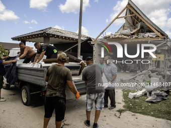 Local residents are cleaning up the residential building in a village in the Kyiv region, heavily damaged during a massive Russian missile a...